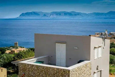 a white house with the ocean in the background at APT NINO in Villa Rosaria Vista Mare Zingaro in Scopello