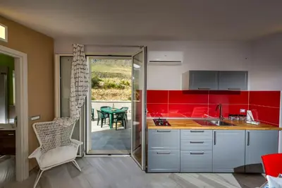 a kitchen with red walls and a table and a chair at APT NINO in Villa Rosaria Vista Mare Zingaro in Scopello