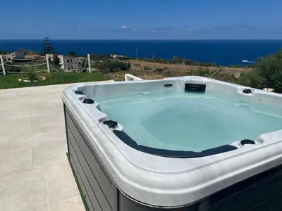 a hot tub on a patio with the ocean in the background at APT NINO in Villa Rosaria Vista Mare Zingaro in Scopello