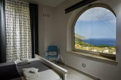 a bedroom with a large window with a bed and a chair at APT Marta in Villa Rosaria Vista Mare Zingaro in Scopello
