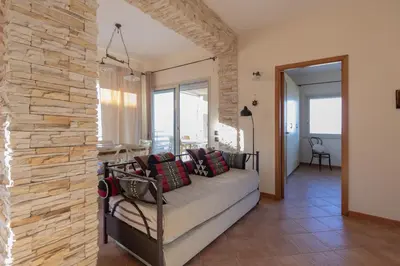 a living room with a couch against a stone wall at Visitsicilia Sabbia Dorata in Alcamo Marina