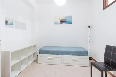 a white bedroom with a bed and a chair at Visitsicilia Saramia in Balestrate