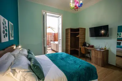 a bedroom with a bed and a desk and a television at Aromatika Suite in Palermo