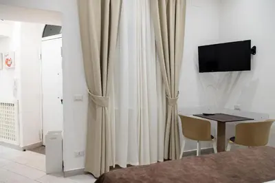 a room with curtains and a desk with a television at Suite 9 Al Massimo Cozy Apt Next to theather in Palermo