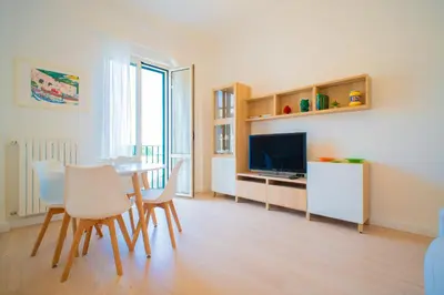 a living room with a table and chairs and a television at Solemar Sicilia - Vista Mare Alla Cala in Palermo