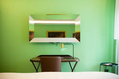 a mirror on a green wall with a table and a chair at Solemar Sicilia - Goethehaus in Palermo