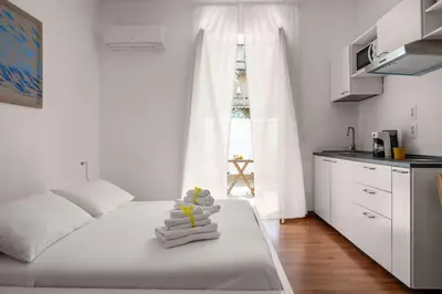 a bedroom with a bed with towels and a kitchen at Sunny studio with terrace in best central area in Palermo