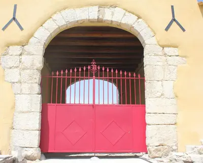 a red gate in a building with an arch at Agriturismo Masseria Castellana in Monreale