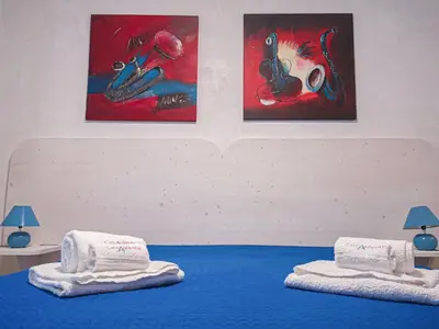 two beds with towels on them in a room with paintings at Casaulente Mare in Alcamo Marina