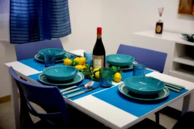 a table with blue plates and a bottle of wine at L'arco Sul Mare in Balestrate