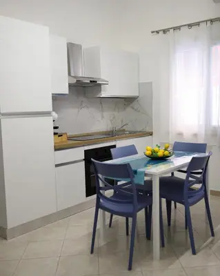 a kitchen with a table with chairs and a bowl of fruit on it at L'arco Sul Mare in Balestrate