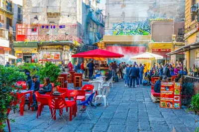 a group of people sitting at tables in a street at Central Post Office Guest House in Palermo