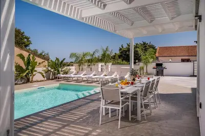 a patio with a table and chairs next to a pool at Rosvì Villa in Castellammare del Golfo