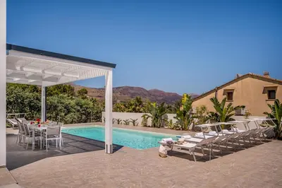 a patio with a table and chairs next to a pool at Rosvì Villa in Castellammare del Golfo