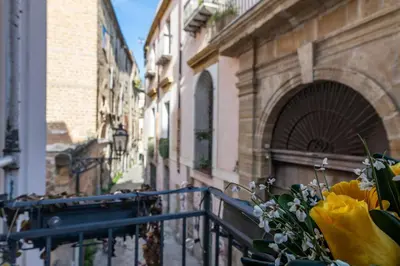 a balcony with a bunch of yellow flowers next to a building at GuestHost - Al Cassaro Holiday Home in Palermo