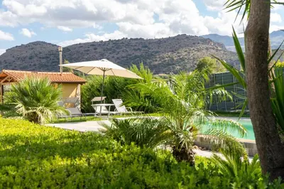 a patio with an umbrella and chairs and a pool at Villa Oasi della Pace based in Partinico in Partinico