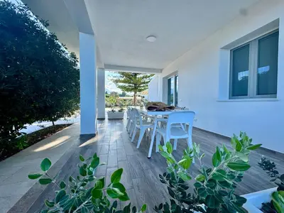 a porch with a table and chairs on it at Al Grande Pino - Private pool, Jacuzzi and amazing Sunset in Campofelice di Roccella