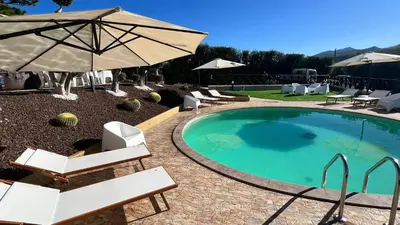 a swimming pool with chairs and an umbrella at Al Grande Pino - Private pool, Jacuzzi and amazing Sunset in Campofelice di Roccella
