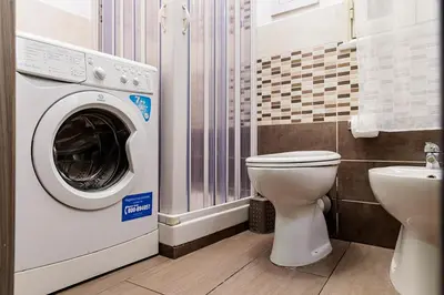 a bathroom with a washing machine and a toilet at Meschita Little House in Palermo