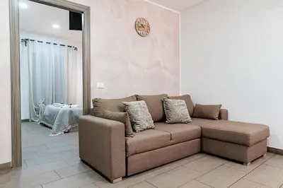 a brown couch in a living room with a clock on the wall at Meschita Little House in Palermo