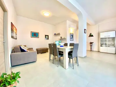 a dining room and living room with a table and chairs at Villa dei Gerani, a 500 mt dal mare in Alcamo