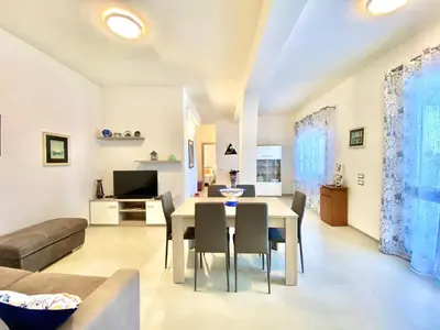 a dining room and living room with a table and chairs at Villa dei Gerani, a 500 mt dal mare in Alcamo