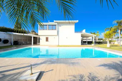 a swimming pool in front of a house at Private Villa, Sun & Pool in Mandra Capreria