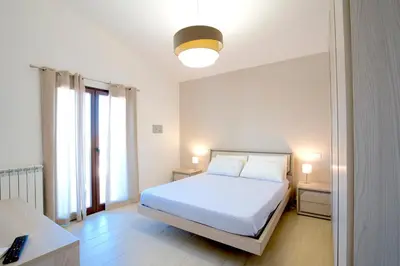 a bedroom with a white bed and two windows at Private Villa, Sun & Pool in Mandra Capreria