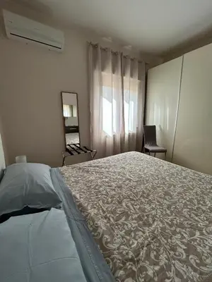 a white bedroom with a bed and a chair at Casa Vacanze Letizia in Lercara Friddi