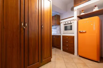 a kitchen with an orange refrigerator and wooden cabinets at GuestHost - Casa Giacomo in central Palermo in Palermo