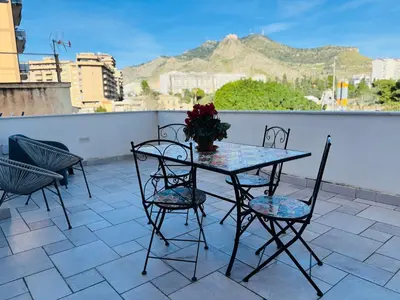 a table with chairs and a vase of flowers on a balcony at Sampolo Rooftop - Palermo View in Palermo