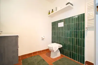 a bathroom with a toilet and a green tiled wall at Solemar Sicilia - Casa Alba in Santa Flavia