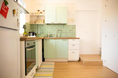 a kitchen with white cabinets and green tiles at Solemar Sicilia - Casa Alba in Santa Flavia