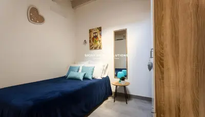 a small bedroom with a blue bed and a table at Charming Loft near the Sea - Castellammare del Golfo by Sicily Home Solutions in Castellammare del Golfo
