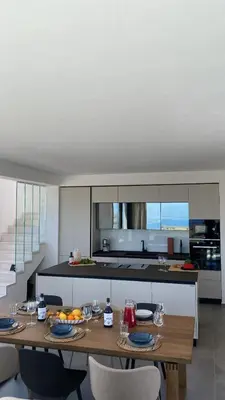 a kitchen with a wooden table with chairs and a counter at Villa Muntaja in Scopello