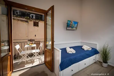 a bedroom with a bed and a balcony with a table at Borgo La Chiusa in Castellammare del Golfo