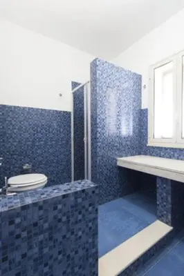 a blue tiled bathroom with a toilet and a sink at Apartment Villa am Meer Trappeto by Interhome in Trappeto