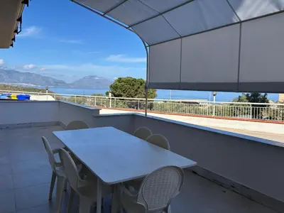 a table and chairs on a balcony with a view of the ocean at Apartment für 6 oder 7 Personen by Interhome in Balestrate