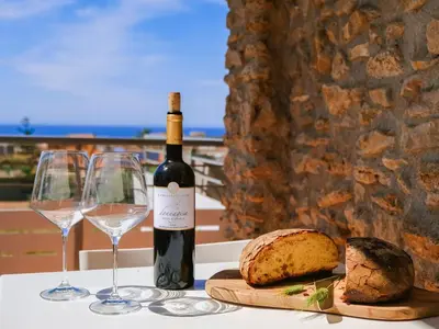 a bottle of wine and glasses on a table with bread at Apartment Lila Wohnung mit Schwimmbad und Meerblick by Interhome in Balestrate