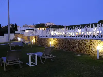 a patio with chairs and a stone wall at night at Apartment Lila Wohnung mit Schwimmbad und Meerblick by Interhome in Balestrate