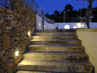 a set of stone stairs in front of a stone wall with lights at Apartment Lila Wohnung mit Schwimmbad und Meerblick by Interhome in Balestrate