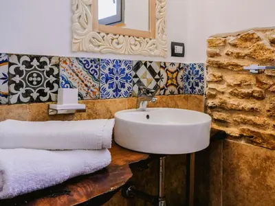 a bathroom with a sink and a mirror and tiles at Apartment Wohnung in Balestrate mit Schwimmbad und Meerblick by Interhome in Balestrate