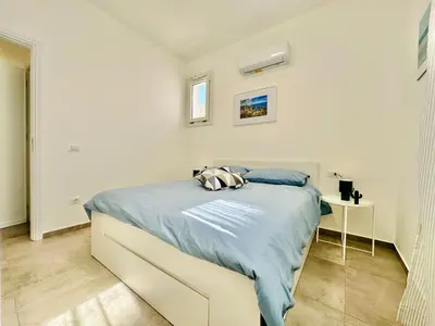 a white bedroom with a bed and a table at Apartment Sea Life Giulia- 200 m vom Strand entfernt by Interhome in Alcamo Marina