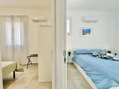 a white bedroom with a blue bed and a window at Apartment Sea Life Giulia- 200 m vom Strand entfernt by Interhome in Alcamo Marina