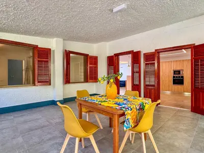 a dining room with a table and yellow chairs at Apartment Villa Sao- Scopello- Punta Pispisa by Interhome in Scopello