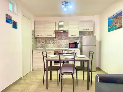 a kitchen with a table and chairs and a refrigerator at Apartment GS Urlaub del Golfo Haus mit Jacuzzi by Interhome in Castellammare del Golfo