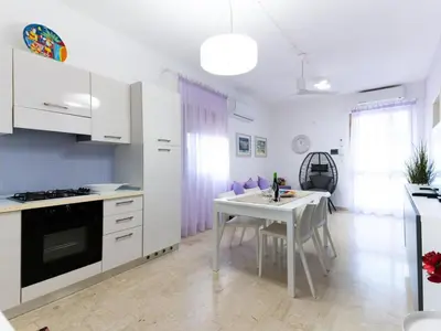 a kitchen with white cabinets and a table and a dining room at Holiday Home Villa Panorama del Golfo mit privatem Pool und Grillplatz by Interhome in Balestrate