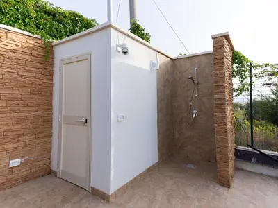 a shower with a white door next to a brick wall at Holiday Home Villa Panorama del Golfo mit privatem Pool und Grillplatz by Interhome in Balestrate