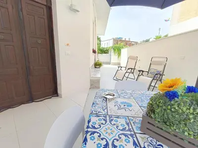 a patio with a table and chairs and a door at Per Famiglie ed Amici a 3 minuti a piedi dal mare Rosso Corallo Alcamo Marina in Alcamo Marina