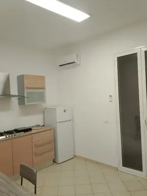 a white kitchen with a refrigerator and a table at Fabian Appartament in Bagheria